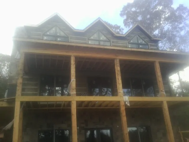 Dormers and porch framing on a large log home under construction — Roof Coating work by our crew in Lake Huntington