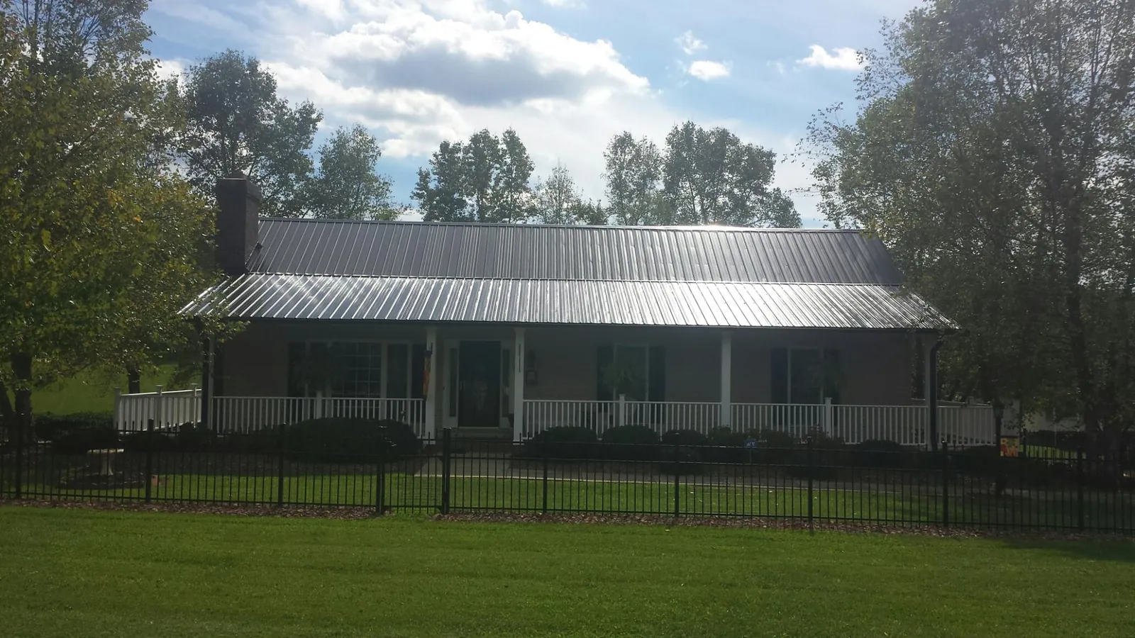 Gray metal roof on a brick ranch with a full width front porch — Gutter Guard Installation work by our crew in Lake Huntington
