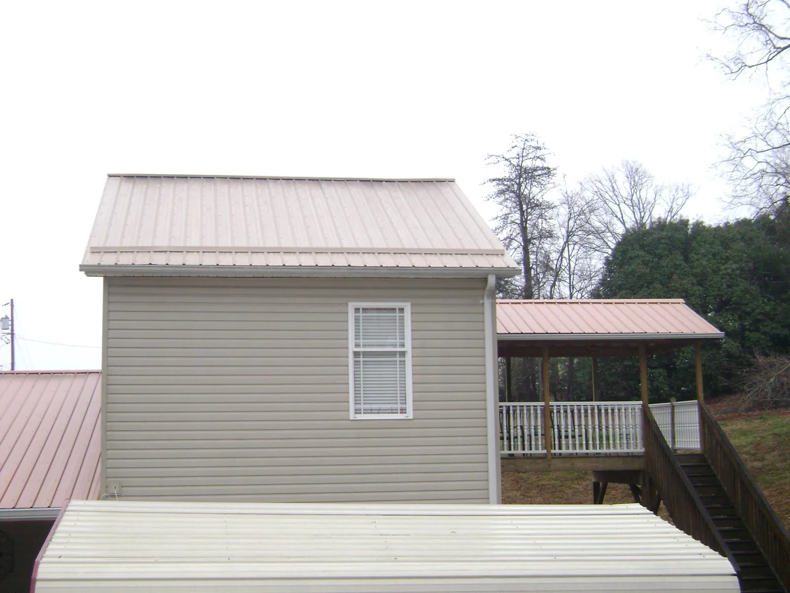 Tan metal roofs on a two story addition and attached porch in Lake Huntington