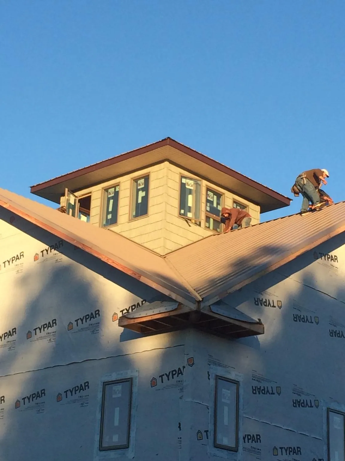 Roofers working around a rooftop cupola on a new metal roof at sunset — Roof Waterproofing in Lake Huntington by Roofing Brothers